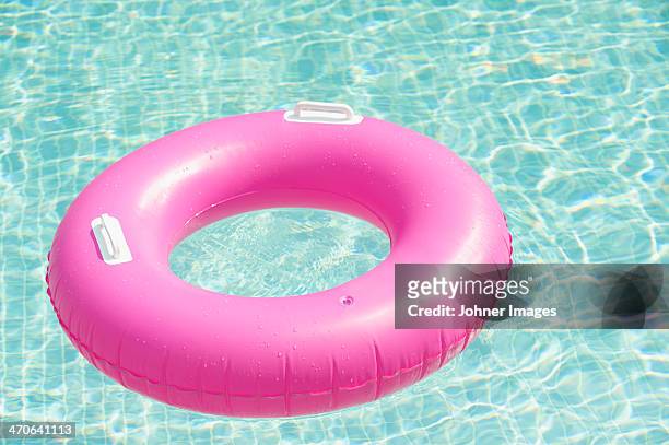 pink inflatable ring floating at swimming pool - float stockfoto's en -beelden