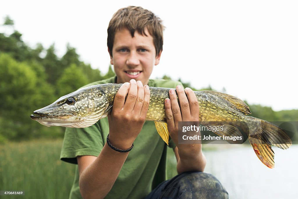 Smiling teenage boy with caught fish