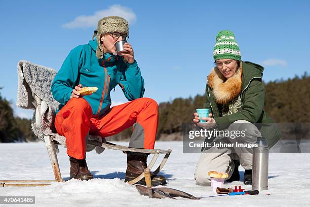 man and woman having food while fishing - stockholm winter stock pictures, royalty-free photos & images