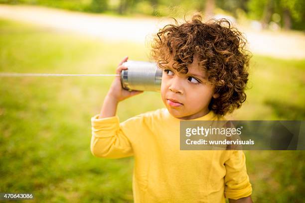 little boy listening to sound through a tin can phone - plåtburkstelefon bildbanksfoton och bilder