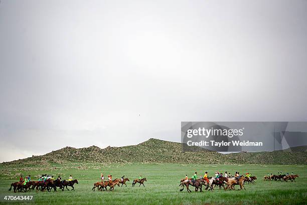 Young jockeys ride their horses out to the starting line for a race during a Naadam festival. Mongolian pastoral herders make up one of the world's...