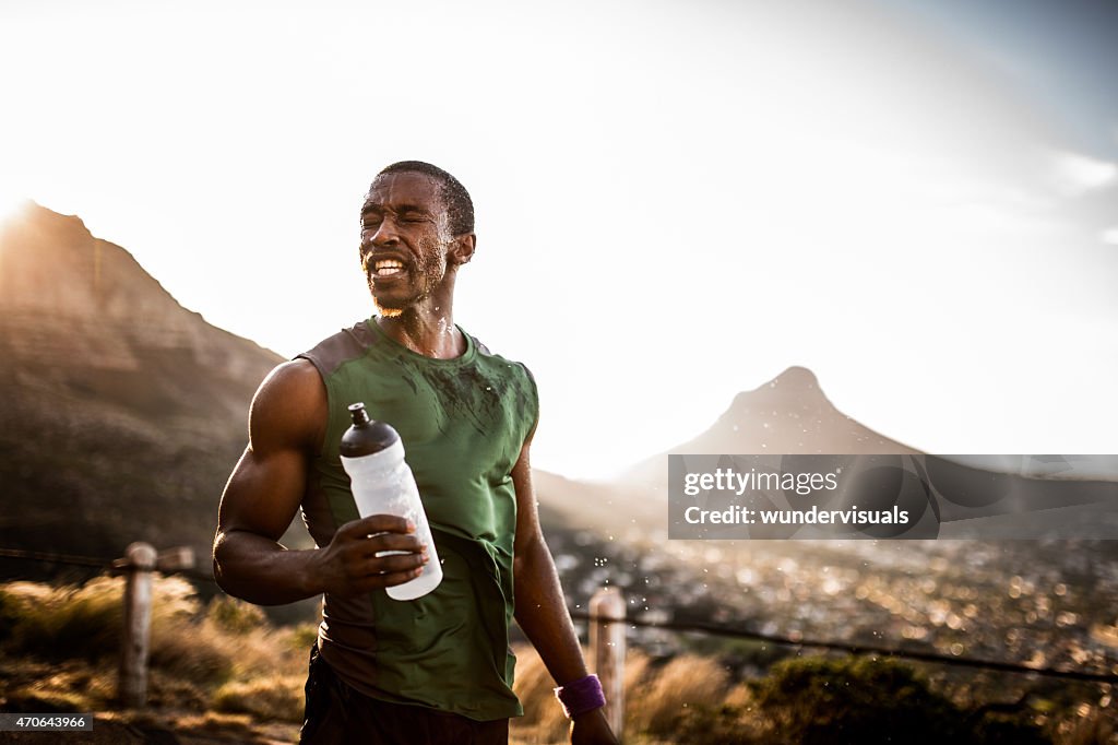 Müde afrikanischen amerikanischen Sportler mit Wasser, sonnenverwöhnte auf seinem Gesicht
