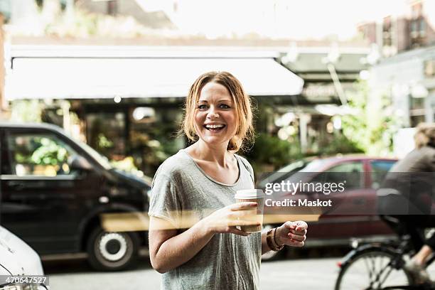 portrait of happy woman holding disposable coffee cup on street - coffee bike stock pictures, royalty-free photos & images