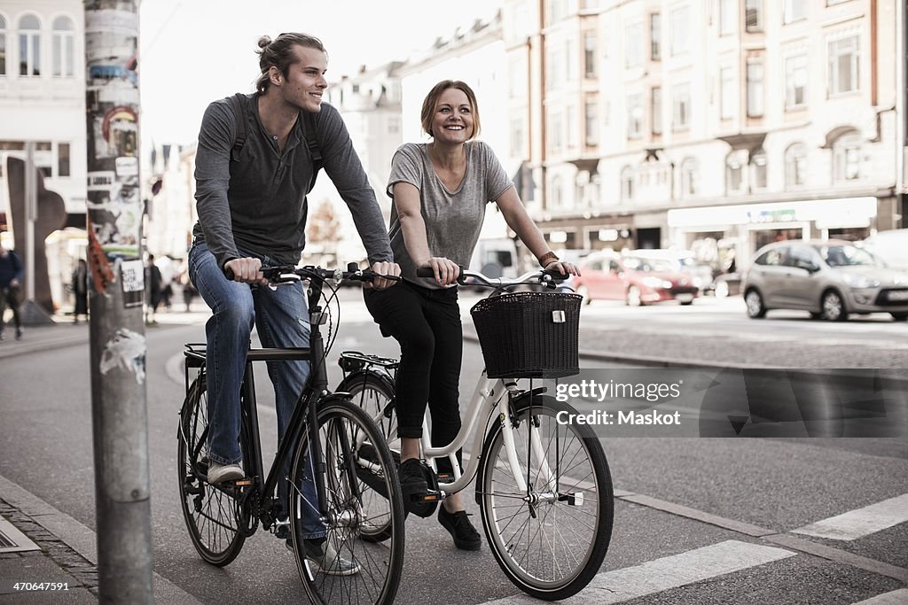 Happy couple riding bicycles on city street