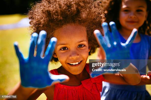 little afro girl showing hands full of blue paint - vingerverf stockfoto's en -beelden