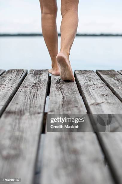 low section of woman walking on pier - ponton photos et images de collection
