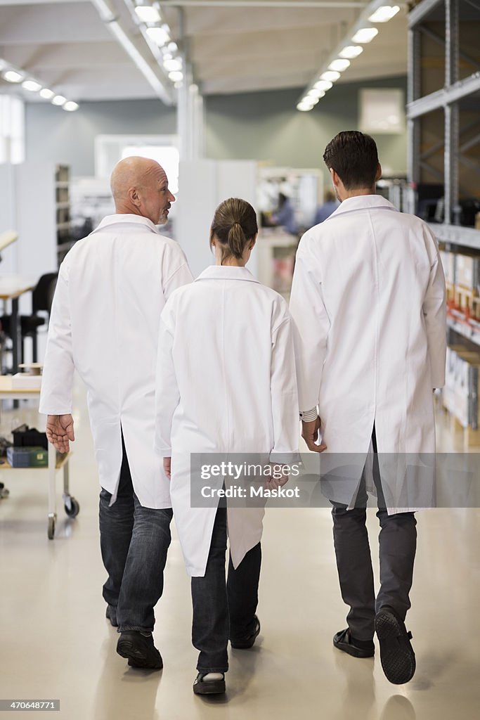 Rear view of engineers walking in factory