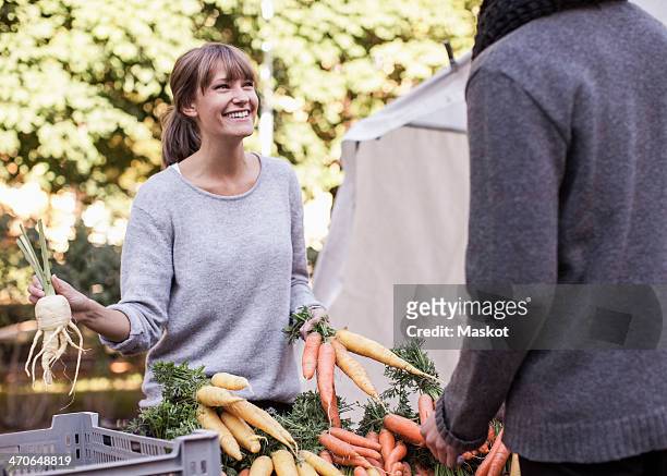 young female vendor selling vegetables at market stall - food market stockfoto's en -beelden
