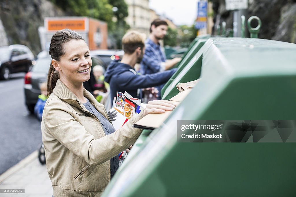 Woman and friends putting recyclable materials into recycling bins