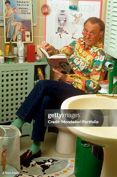 "The imaginative Pugliese show man and musician Renzo Arbore reads a book about the actor Tot, sitting on the toilet of his bathroom, that is...