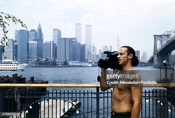 "Italian singer Eros Ramazzotti makes a shot with a shoulder camera on the bank of the East River, near the Brooklyn Bridge, with New York skyline on...