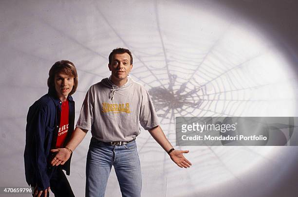 "Mauro Repetto and Max Pezzali, the two members of the pop band 883, pose in a photo studio, against a wall upon which is projected the image of a...