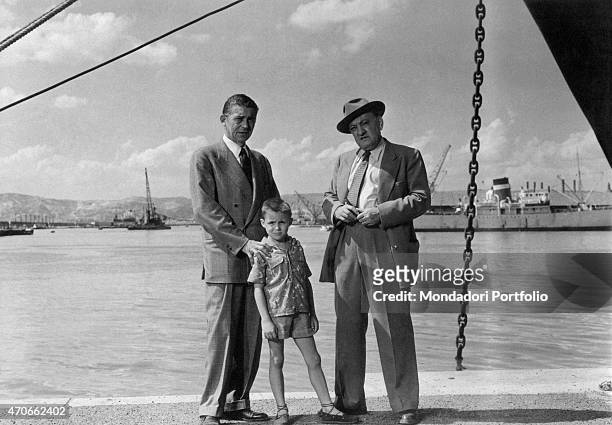 "French actor Jean Servais, as Marc Hourtin, and little Patrice Bergerac as Hourtin's son, pose on the dock of Marseille next to Yves Deniaud as...