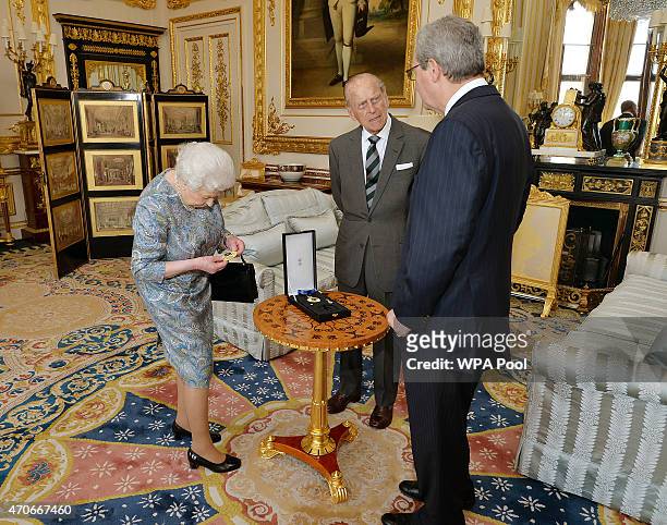 Queen Elizabeth II inspects the Insignia of a Knight of the Order of Australia after presenting it to Prince Philip, Duke of Edinburgh as the...