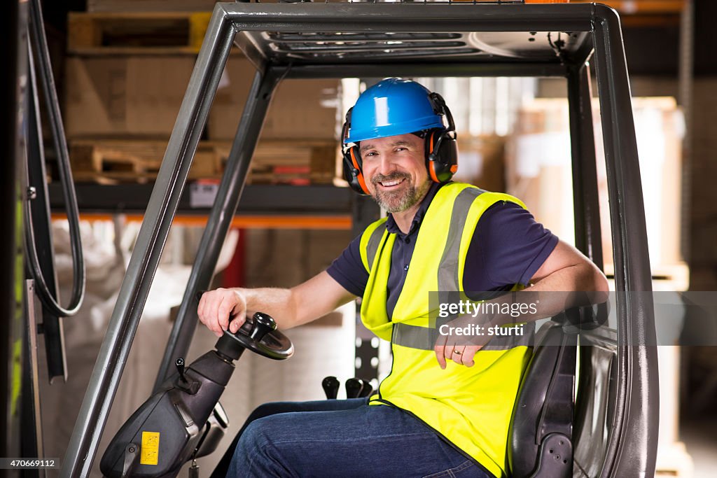 Happy mature forklift truck driver smiling to camera