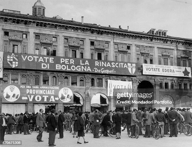 Crowd of people gathered on piazza Maggiore for an election rally. The slogans of Christian Democratic Party , Italian Liberal Party , Italian...