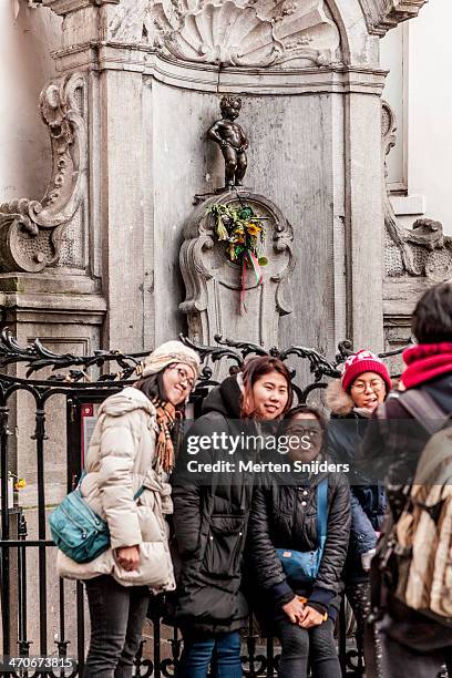 asian tourists posing at manneke pis - manneke pis stock pictures, royalty-free photos & images