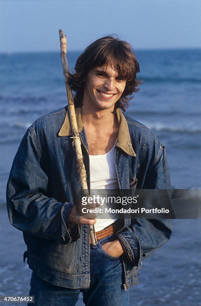 Spanish-Italian actor and singer Miguel Bosé posing smiling at the beach. 1978