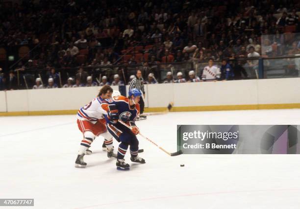 Wayne Gretzky of the Edmonton Oilers skates with the puck as Ron Duguay of the New York Rangers tries to hook him during an NHL game on November 15,...