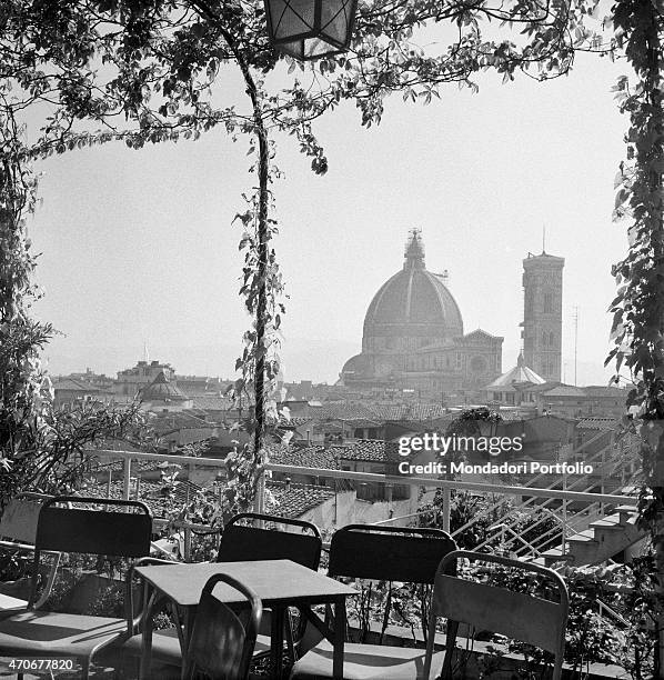 "The cathedral of Santa Maria del Fiore standing beyond a terrace with pergola, chairs and tables. Florence, 1950s "