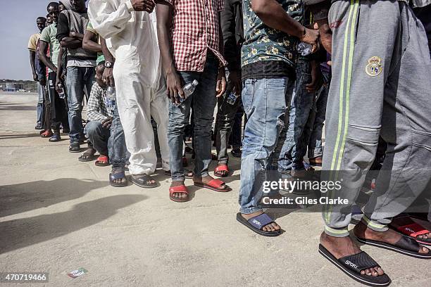 Group of rescued North African migrants wait in line to receive medical treatment and evaluation before being processed in immigration on October 15,...