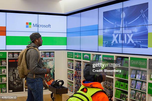 Customers play video games on a Microsoft Corp. Xbox at the company's store in Bellevue, Washington, U.S., on Tuesday, April 21, 2015. Microsoft...