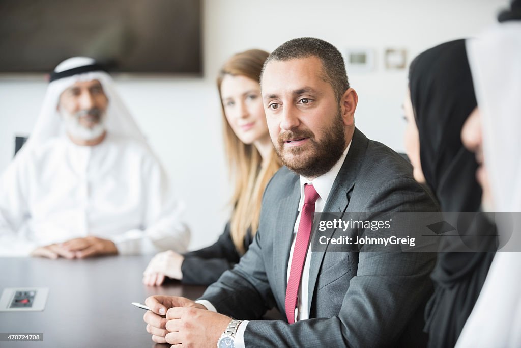Middle Eastern businessman with colleagues at conference table