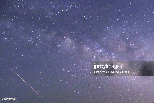 This long-exposure photograph taken on April 23, 2015 on Earth Day shows Lyrids meteors shower passing near the Milky Way in the clear night sky of...