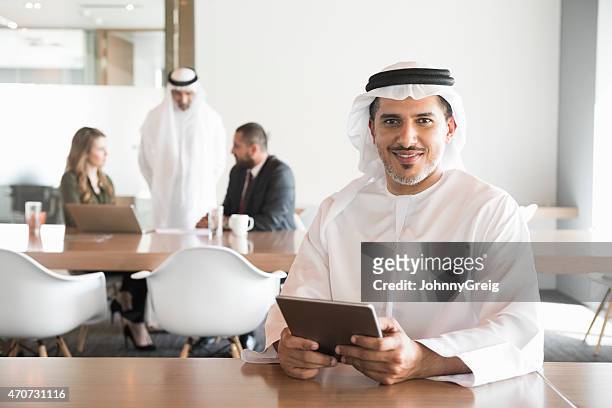 arabi sorridente uomo d'affari con tavoletta digitale in ufficio - emirati arabi uniti foto e immagini stock
