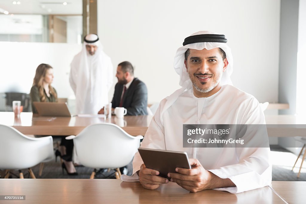 Smiling Arab businessman holding digital tablet in office