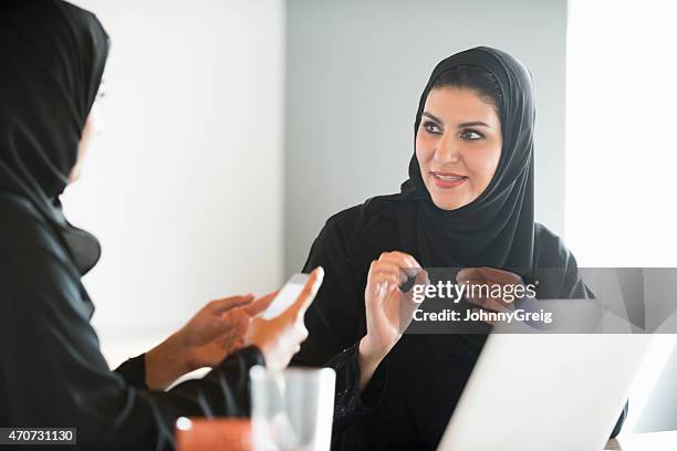 arab businesswomen in traditional clothes discussing in office - arab women stockfoto's en -beelden