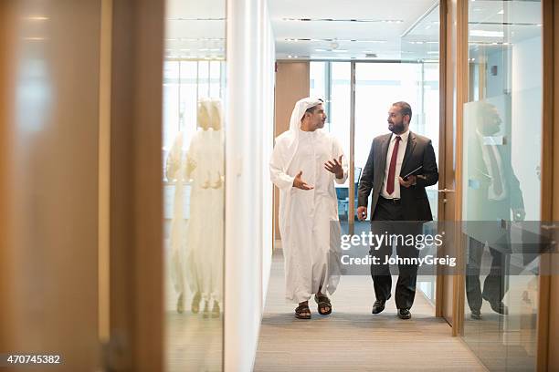 middle eastern businessman discussing office in office corridor - united arab emirates business stock pictures, royalty-free photos & images