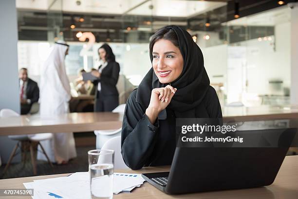junge emiratischen geschäftsfrau wegsehen am konferenztisch - kultur der vereinigten arabischen emirate stock-fotos und bilder