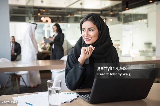 emirati joven empresaria mirando lejos en la mesa de conferencias - etnias de oriente medio fotografías e imágenes de stock