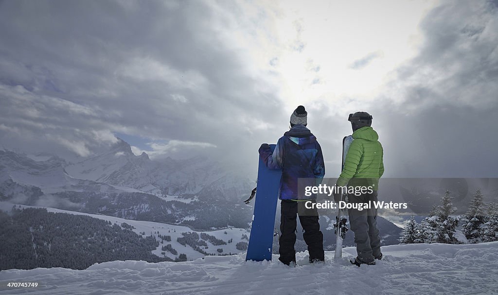 Skier and snowboarder look out over The Alps.