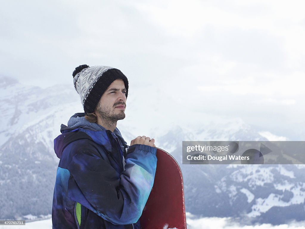 Snowboarder standing with board in The Alps.