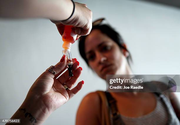 Yenisley Dieppa waits as a sales associate fills her electronic cigarette with flavored E liquid at the Vapor Shark store on February 20, 2014 in...