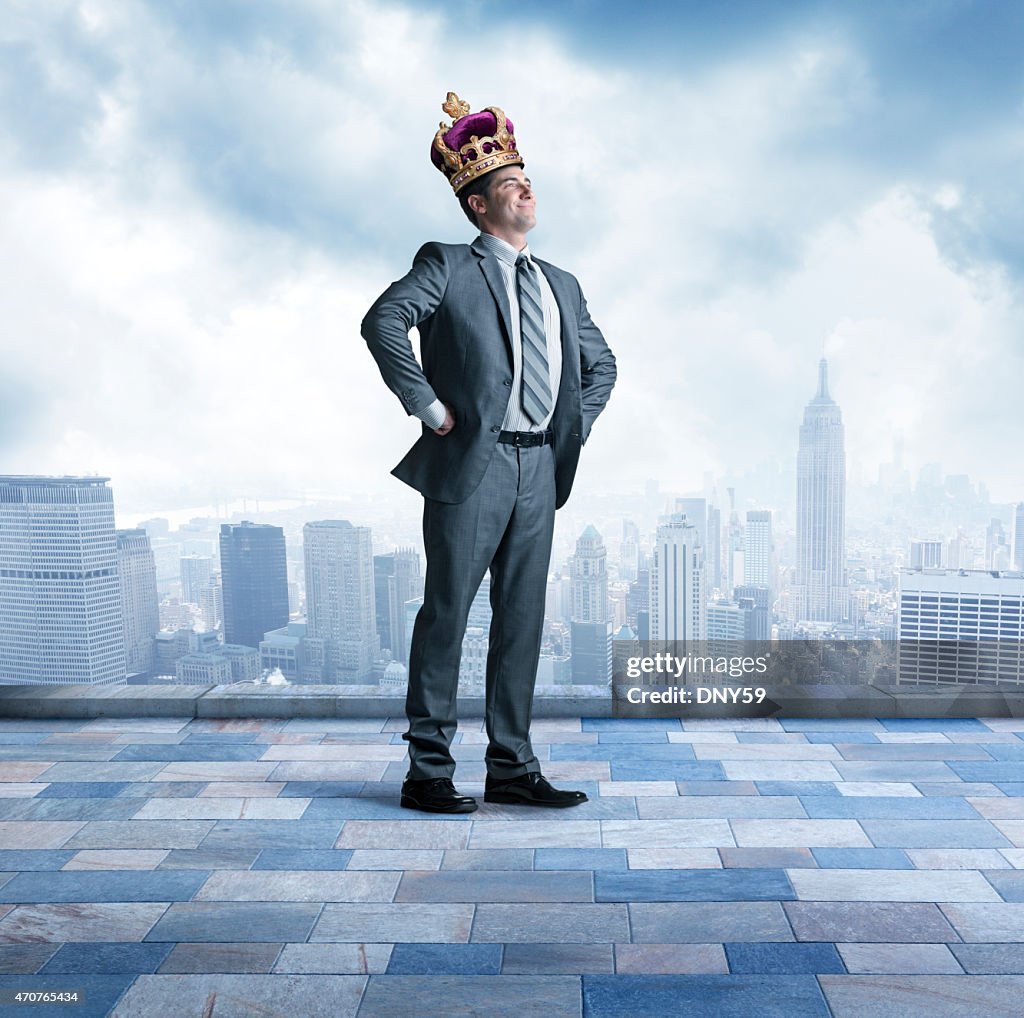 Businessman proudly wearing a crown above big city skyline