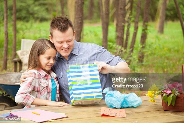 dad opens father's day gift from daughter outdoors. child, parent. - open day 9 bildbanksfoton och bilder