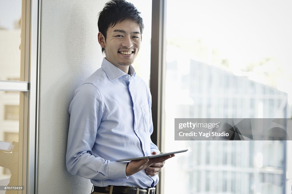 Smiling businessman holding digital tablet