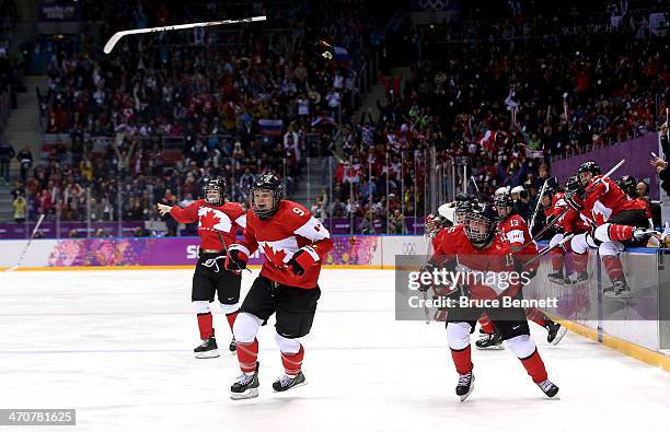 Jennifer Wakefield and Melodie Daoust of Canada celebrate with teammates after defeating the United States 3-2 in overtime during the Ice Hockey...