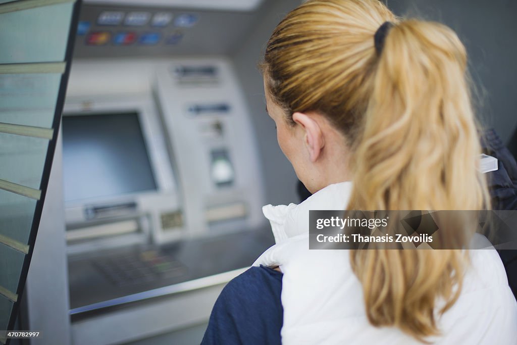 Young woman in front of a Automated teller machine