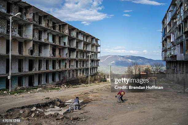 Boys play on a street next to a building destroyed by war more than twenty years earlier on April 18, 2015 in Shushi, Nagorno-Karabakh. Since signing...