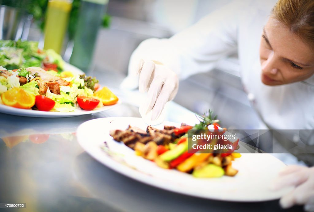 Professional female chef serving food.