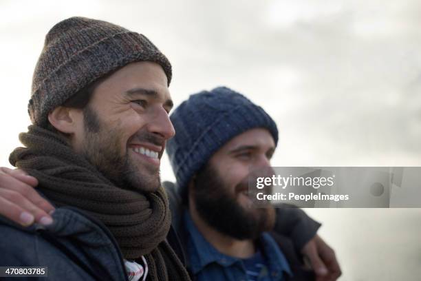 wrapped up gegen das frische meer entspannen - freundschaft männer stock-fotos und bilder