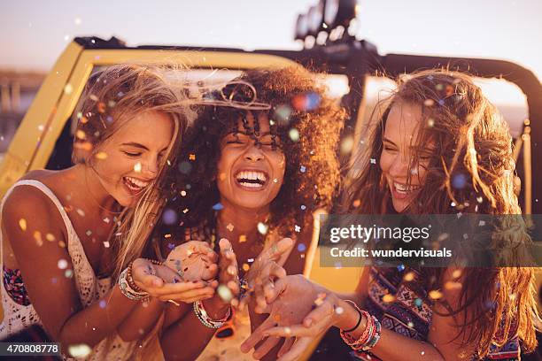 afro girl with frineds on a road trip blowing confetti - multi colored confetti stock pictures, royalty-free photos & images