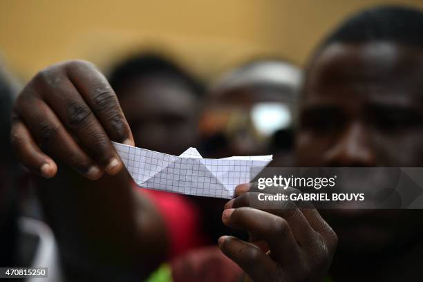 An Asylum seeker holds a paper boat during a demonstration in front of the Italian parliament in Rome, on April 23, 2015. EU leaders gathering in...