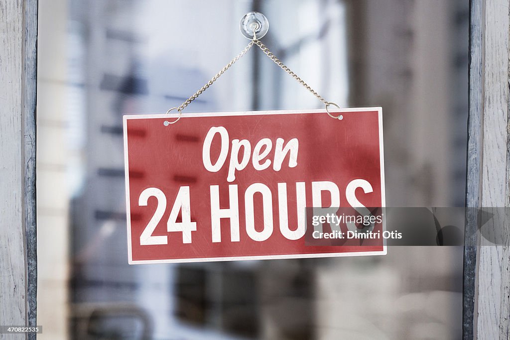 Open 24 hours sign on glass of shop door