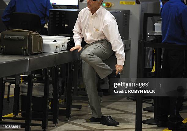 An air traveler puts his shoes back on after passing through the Transportation Security Administration security check at Los Angeles International...