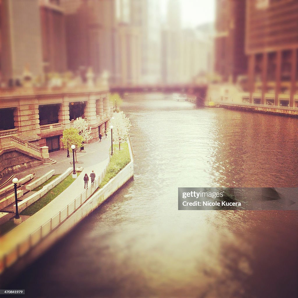 Two people walking together by river in city